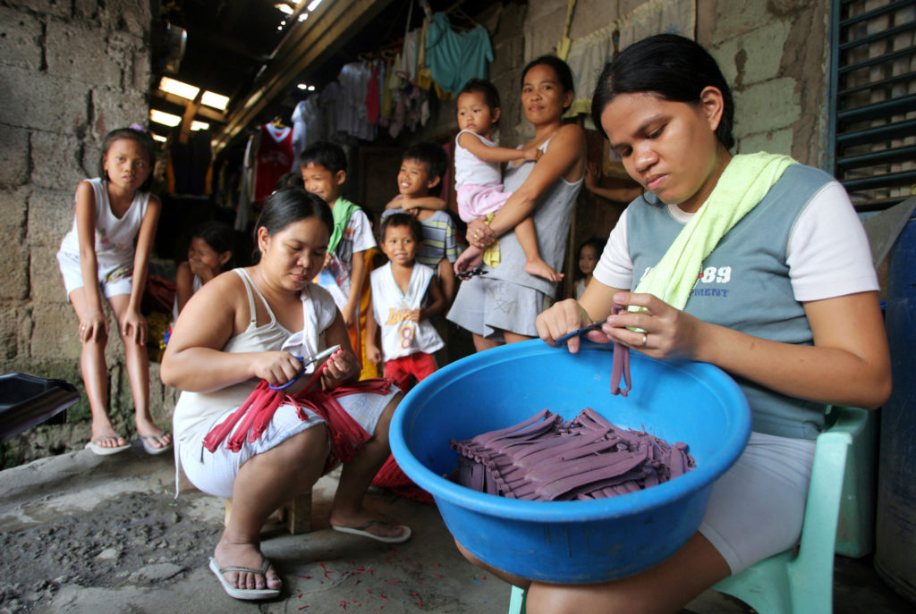 Manila: women cut the remains of the loops of rubber slippers in homework. Credit: Friedrich Stark / Alamy Stock Photo