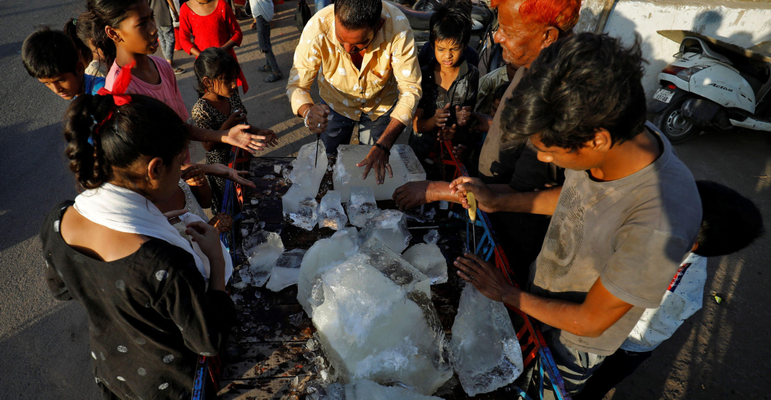 A man breaks a block of ice to distribute it among the residents of a slum during hot weather in Ahmedabad, India, April 28, 2022