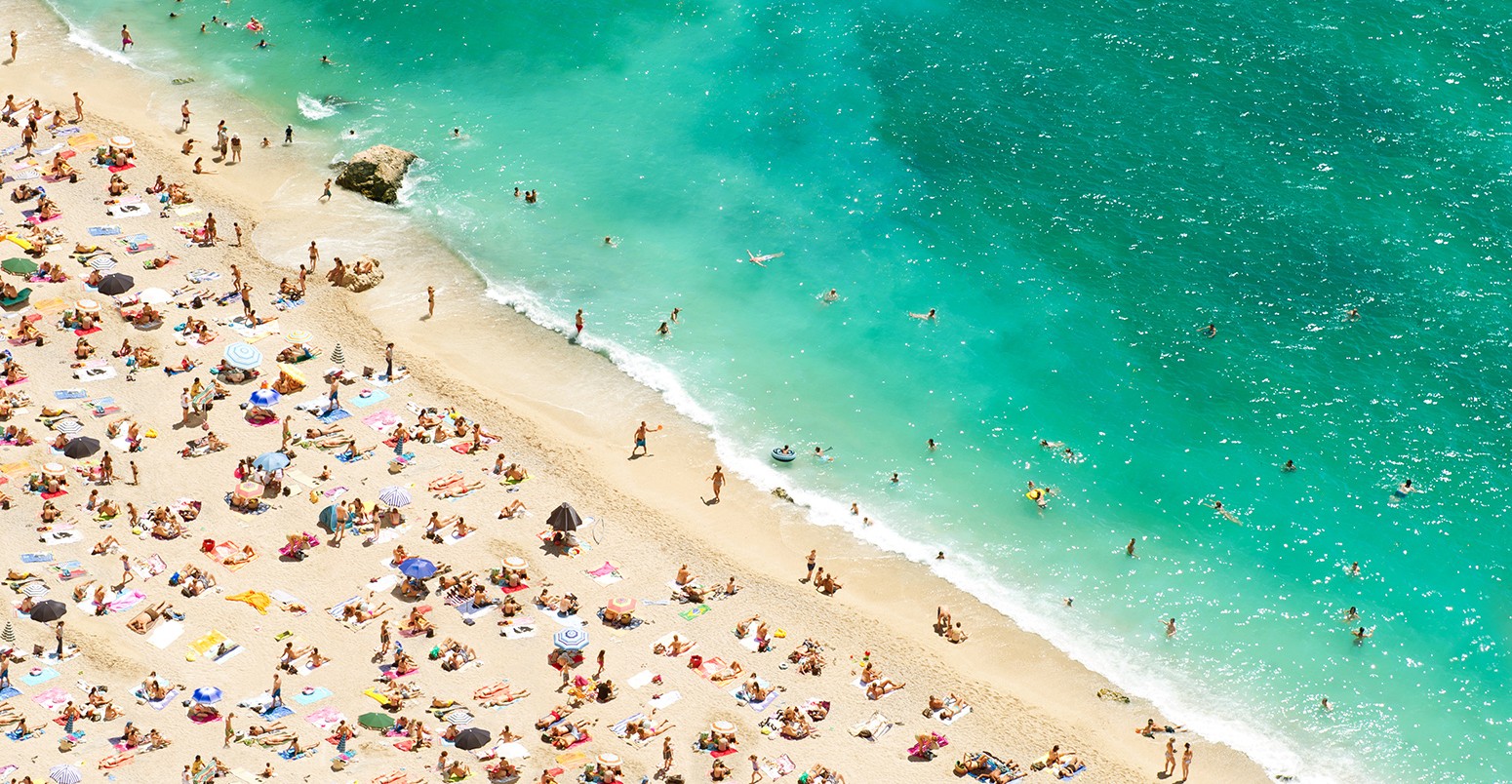 与游客,蔚蓝海岸的海滩日光浴浴床d umbrellas on the hot summer day