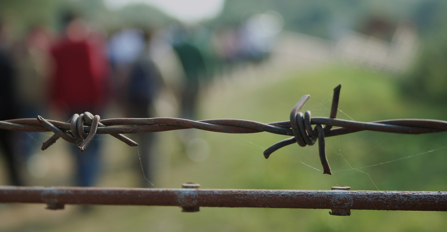Migrants walking away from barbed wire in Syria