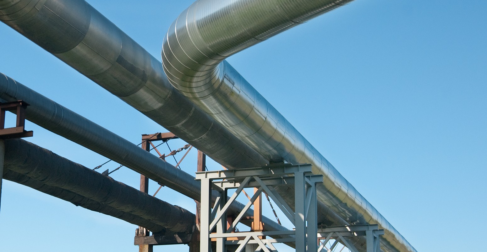 Industrial pipelines on pipe-bridge against blue sky.