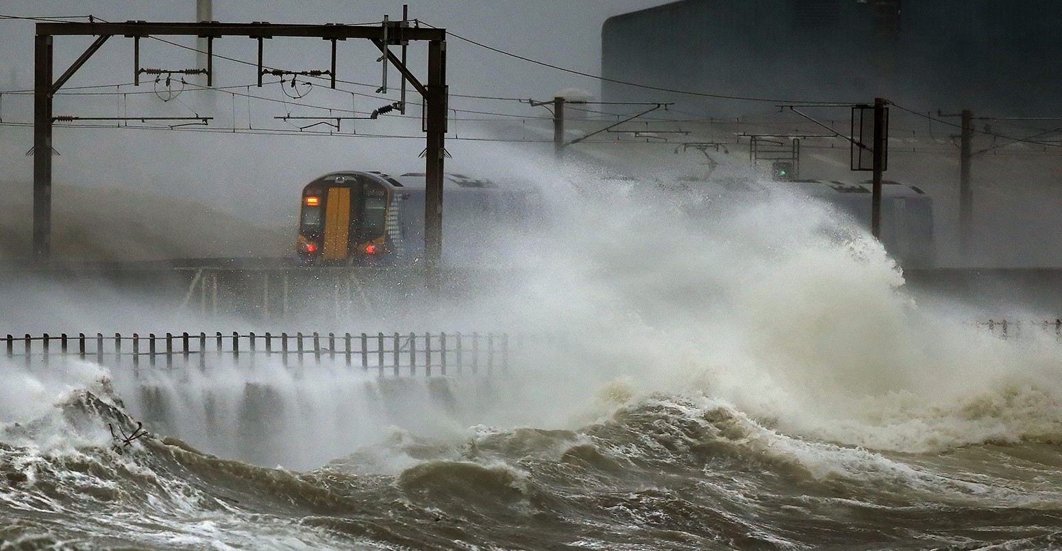A train passes along the coast at Saltcoats in Scotland which is battered by big sea waves 3 January 2014