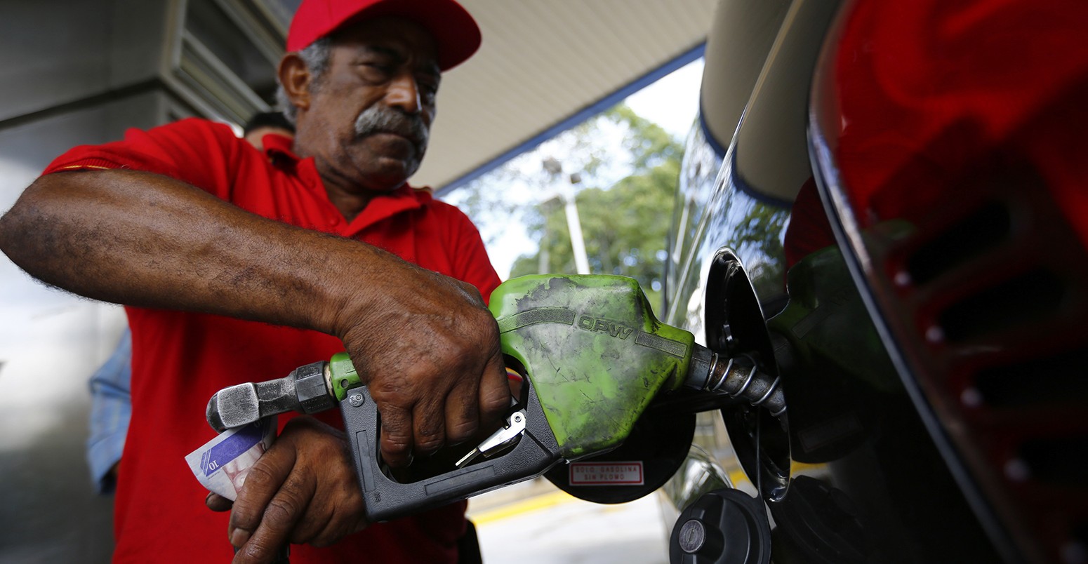 一个man pumps gasoline at a service station in Caracas
