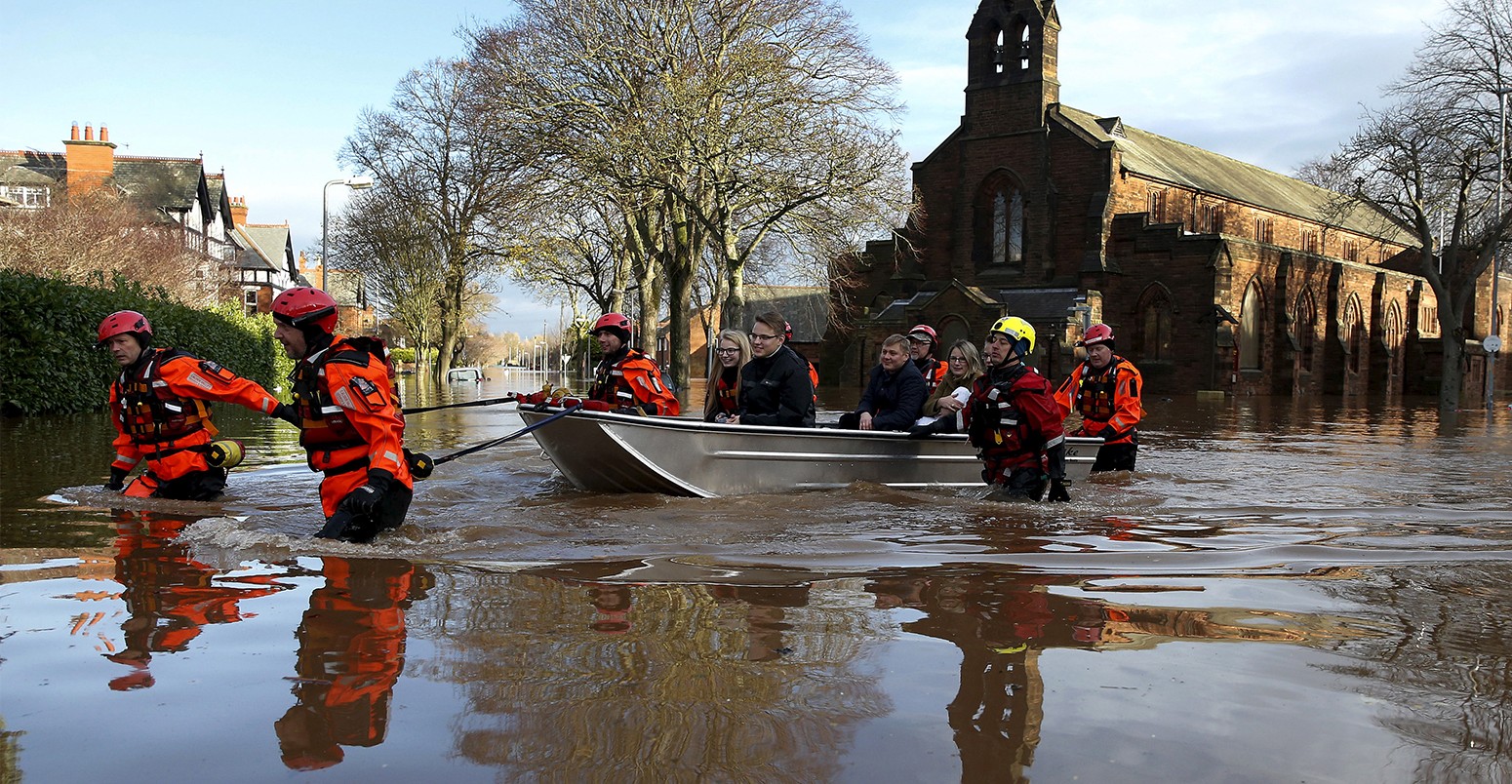 Rescue workers evacuate local residents by boat from a flooded residential street in Carlisle, Britain