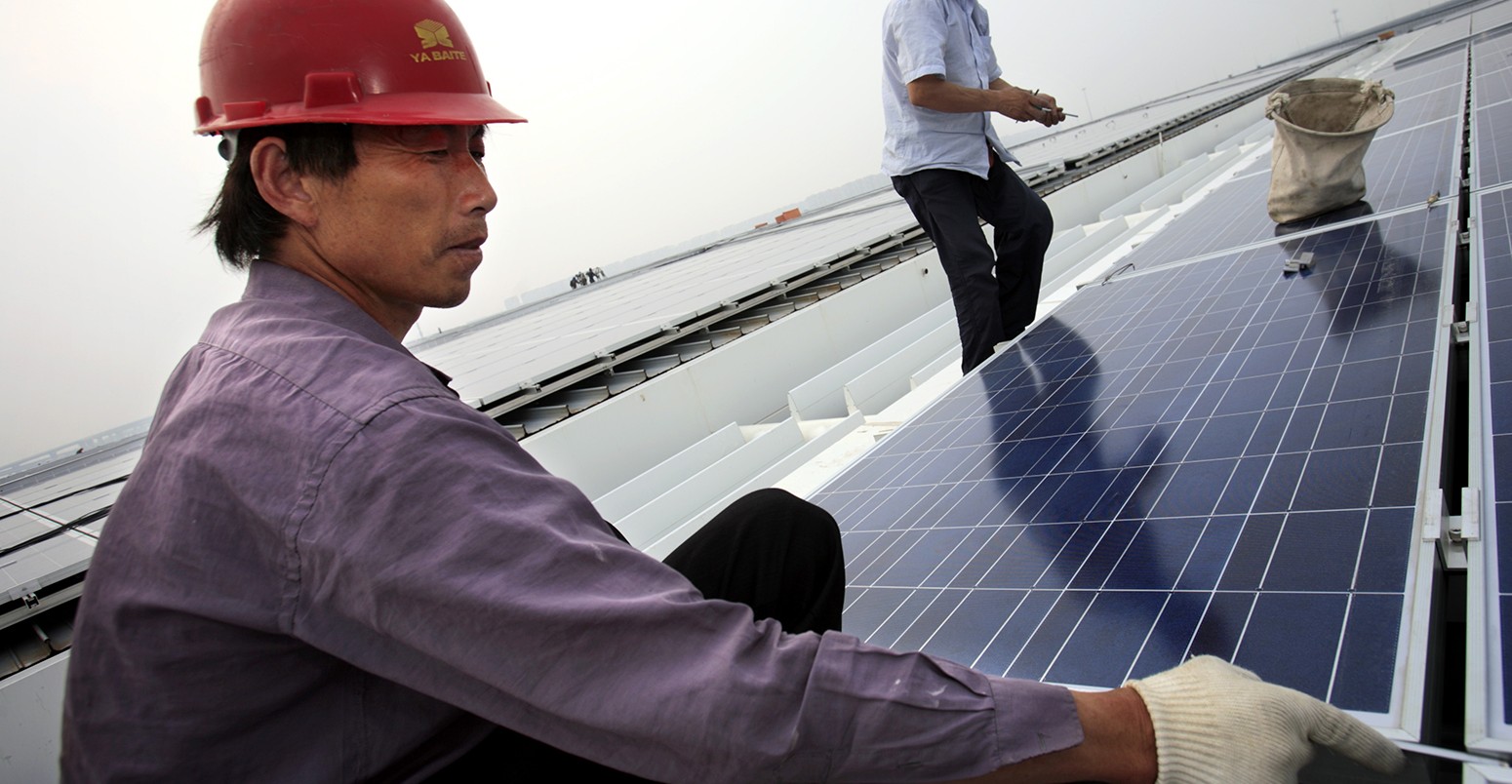 Workers install solar panels on the roofs of the Hongqiao Passenger Rail Terminal in Shanghai, China, 19 May 2010. Credit: Jiri Rezac/The Climate Group.