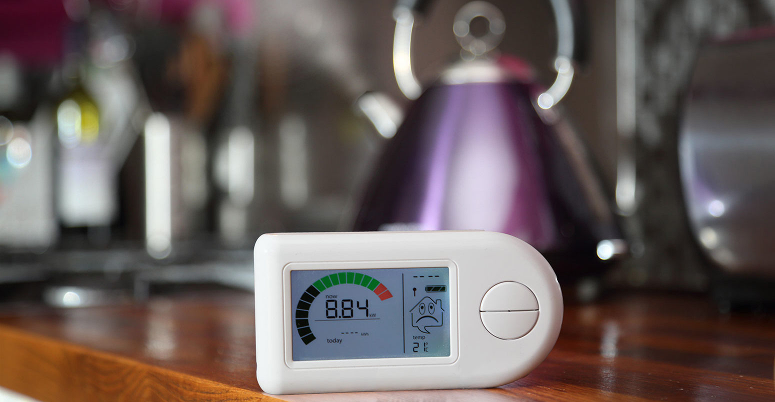 A domestic smart meter sat in front of a kettle.