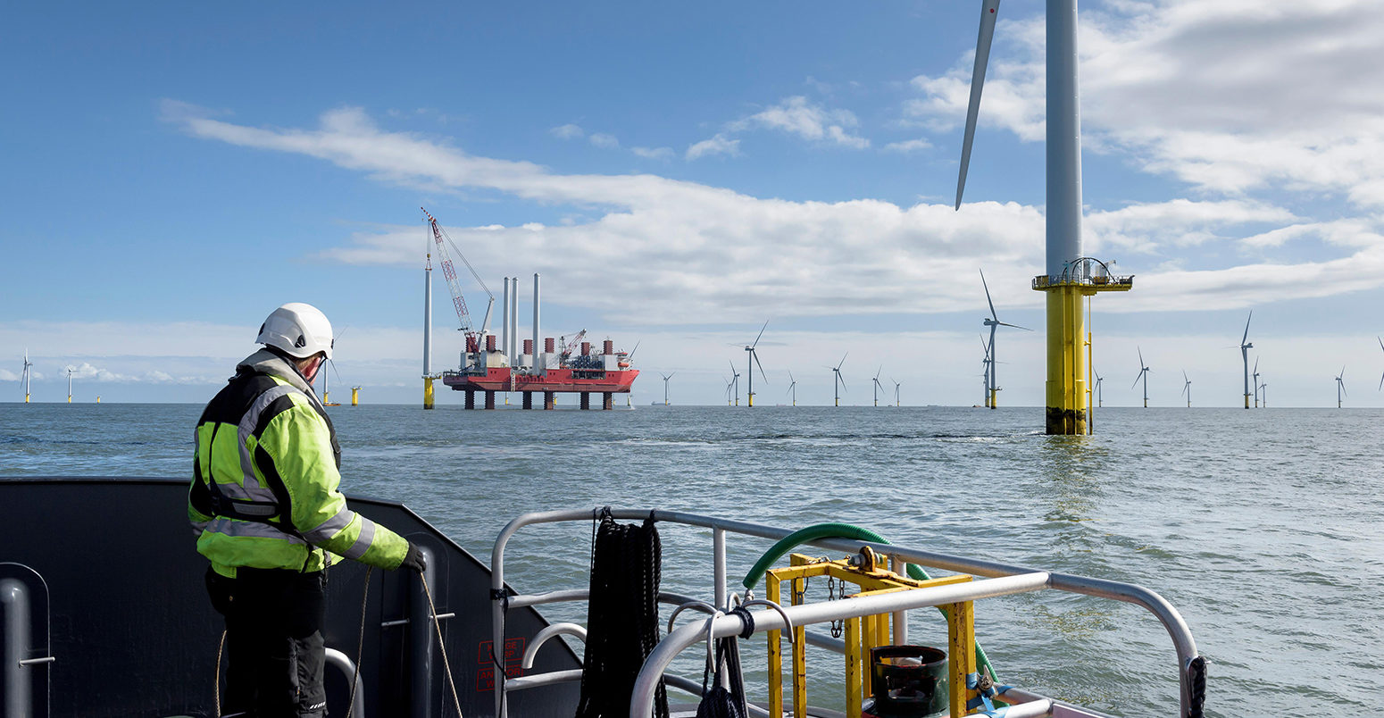 F1HEX0 Worker looking out from ship to offshore wind farm and construction ship.