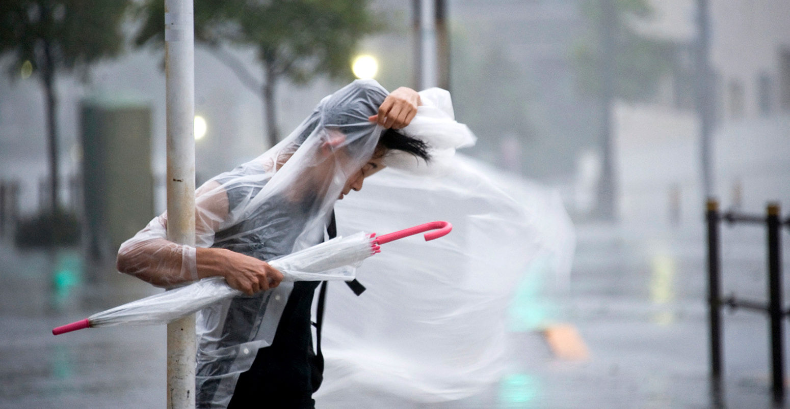 A woman clings on as typhoon Roke blows through Tokyo, Japan, 21 September 2011. Credit: Robert Gilhooly / Alamy Stock Photo. C7G6KM