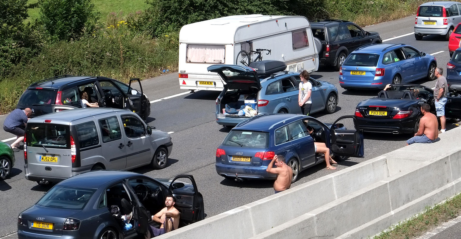 People stuck in a traffic jam in Somerset, UK, leave their cars during a heatwave on 30 July 2016. Credit: Timothy Large / Alamy Stock Photo. GFAT52