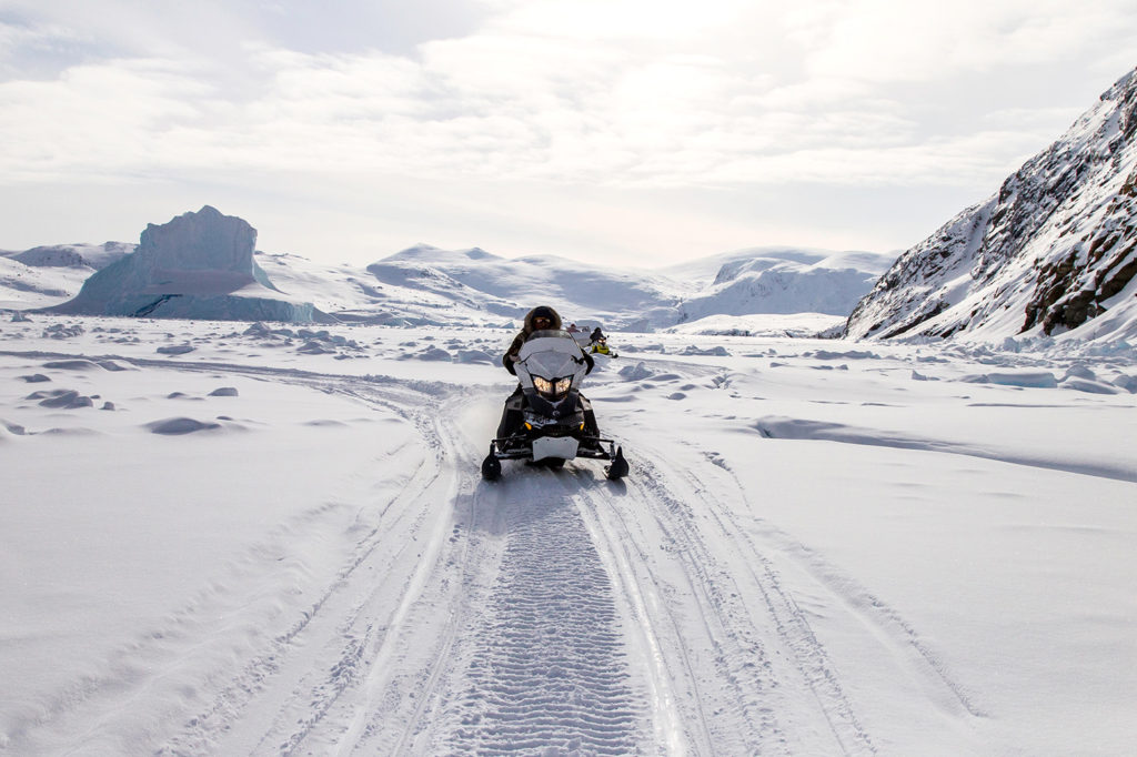 Ski-doo rider traverses a fjord on Baffin Island, Nunavut, Canada. Credit: Russell Millner / Alamy Stock Photo. MG3J49