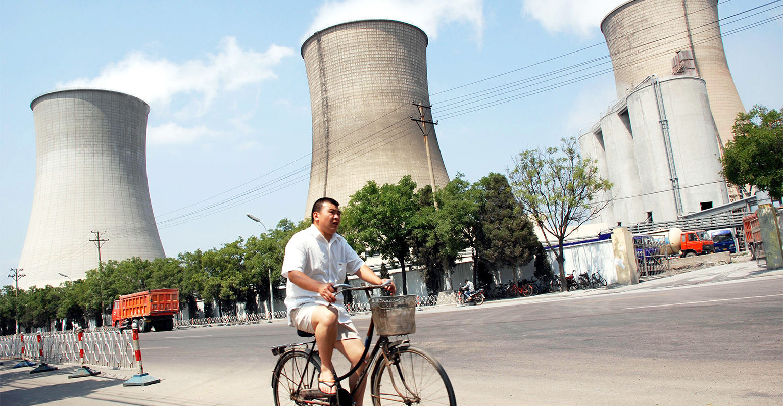 A cyclist rides past a coal-fired power plant in Beijing, China. Credit: Imaginechina Limited / Alamy Stock Photo. W9CEBT