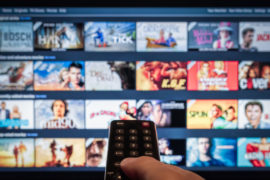 A remote control pointed to a smart tv showing a selection of on-demand video streaming services