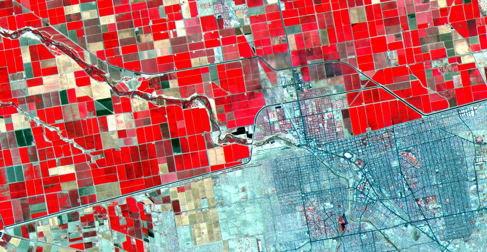 Satellite image showing the Dramatic differences in land use patterns on the US - Mexico border. Lush, regularly gridded agricultural fields on the U.S. side contrast with the more barren fields of Mexico.
