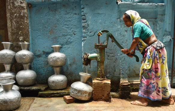 2019年5月20日，孟加拉国达卡，一名妇女在热浪中从井中取水。图片来源:新华社/ Alamy Stock Photo。