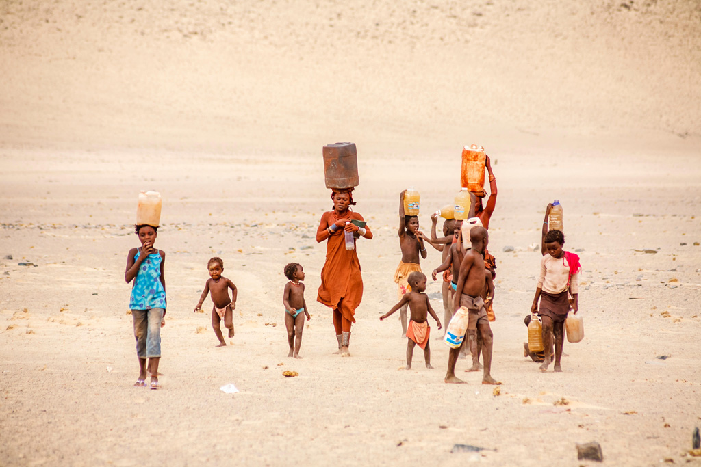 Himba woman and children working carrying water to a village.