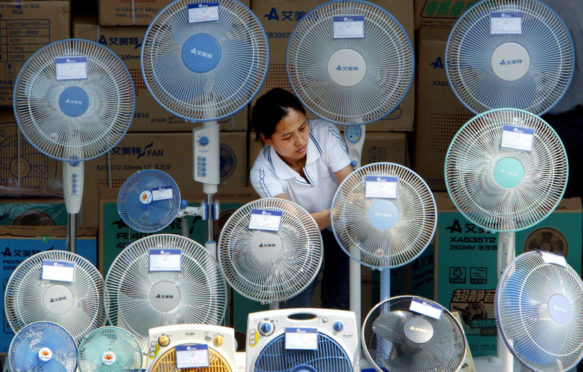 一名中国妇女在北京的一个室外摊位清洁电风扇。