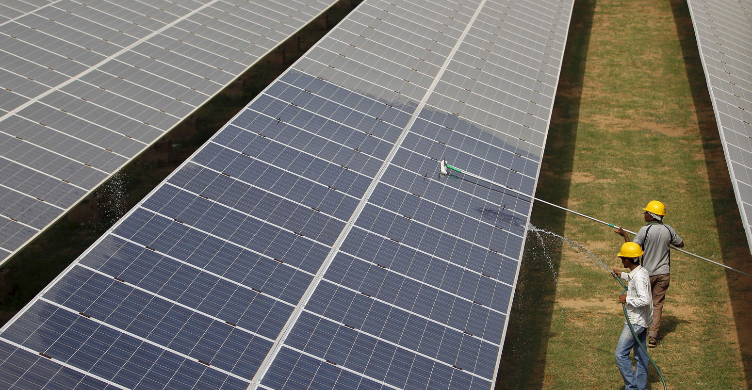 Workers clean photovoltaic panels inside a solar power plant in Gujarat, India.