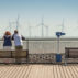 游客在斯基涅斯码头享受炎热的天气，观看海上风电场