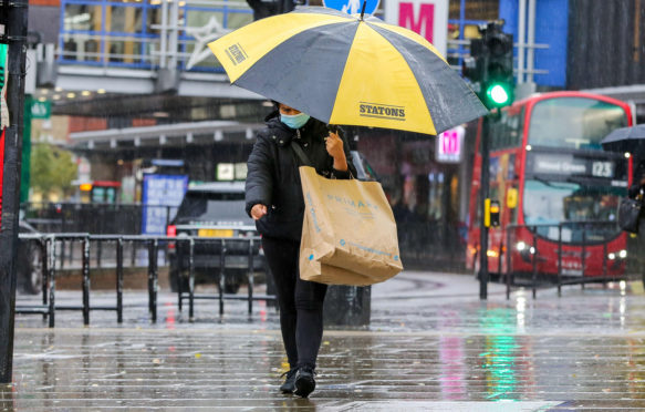 一个购物者戴着口罩，遮雨遮雨，一把雨伞，一个雨天，一个风雨交加的日子，由风暴引起的亚历克斯