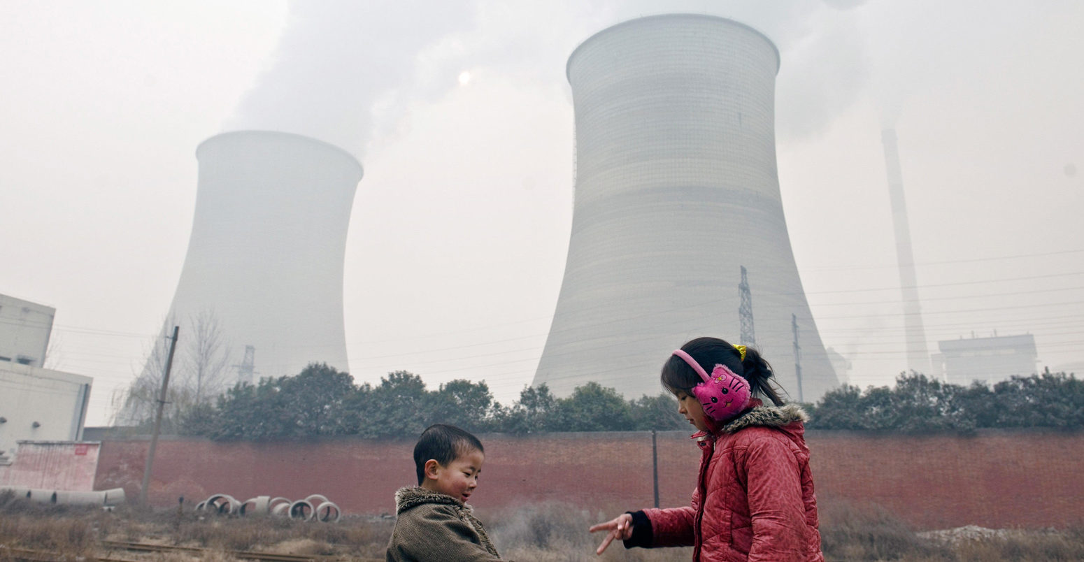 Two-young-kids-play-the-finger-guessing-game-near-cooling-towers-and-chimneys-discharing-smoke-at-a-coal-fired-power-plant-in-heavy-smog-in-Luoyang-city-China