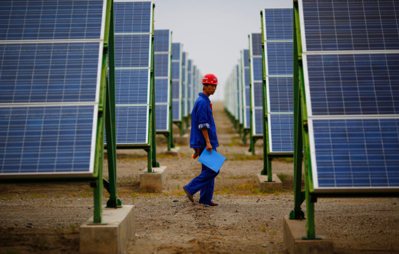 一名工人在敦煌一家太阳能发电厂检查太阳能电池板