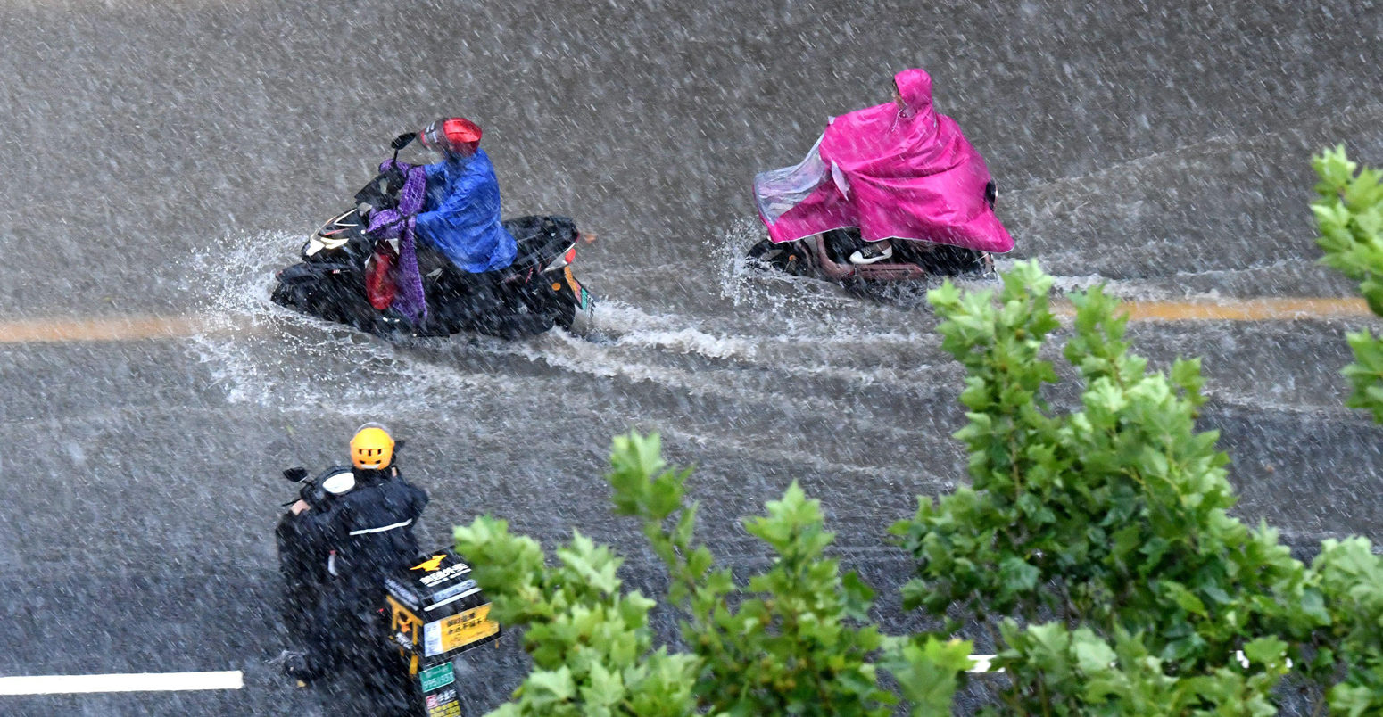 暴雨过后，人们在郑州一条浸水的道路上骑行