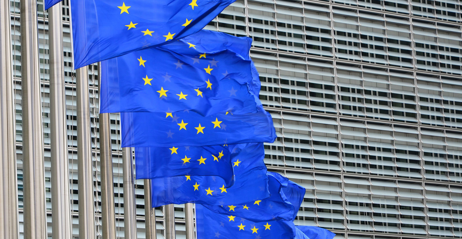 Row of billowing blue European Union flags outside the EU headquarters Berlaymont building