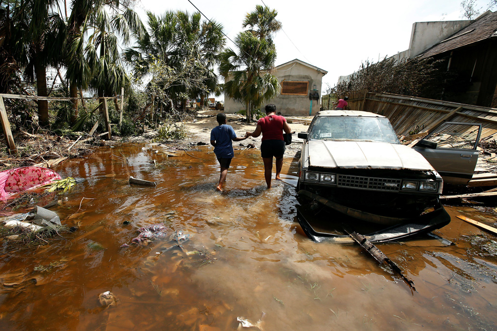 一个女人和一个孩子走进他们淹没了房子in the Bahamas after Hurricane Matthew