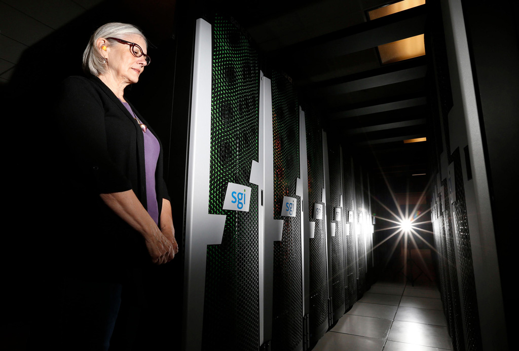 Jill Dunbar of Computer Sciences Corp. stands next to racks of SGI servers that make up the huge Pleiades supercomputer in the NASA Advanced Supercomputing Facility