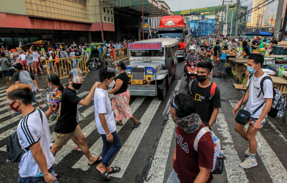 2021年3月，在马尼拉一条繁忙的街道上，人们戴着防护面具