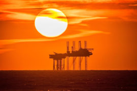 英国绍斯波特海岸线外的汉密尔顿石油钻井平台后面，夕阳倾泻入地平线