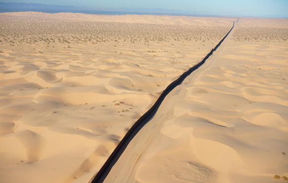 国际边界：墨西哥 - 美国（鸟瞰图）。墨西哥巴哈加利福尼亚州索诺兰沙漠的阿尔贡·沙丘（墙壁左）