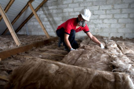 A worker lays loft insulation in the attic of a residential property in Cornwall, UK