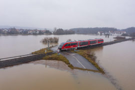 Train-passing-through-a-flooded-road-in-Germany,-February-2021