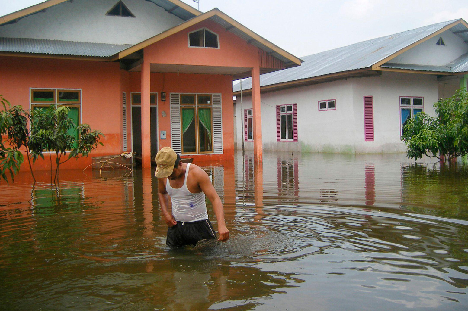 A villager walks in front of his flooded house in Riau province, Indonesia_2E7407R