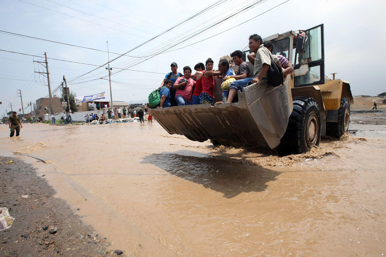 People cross a flooded road after the overflow of the Rimac river in Peru