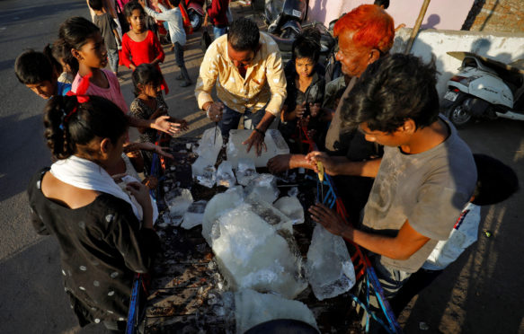 一名男子在印度艾哈迈达巴德（Ahmedab​​ad），2022年4月28日，在炎热的天气中打破一块冰块将其分配在贫民窟的居民中