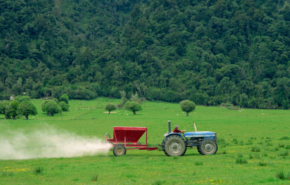 农民在田野上喷洒肥料，以在新西兰放牧绵羊