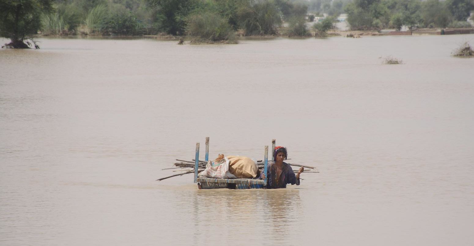 A woman carries her belongings through flood water in Rajanpur, Pakistan in August, 2022