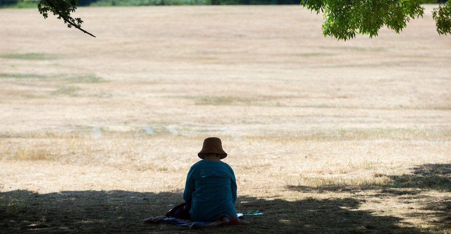 A woman sits in the shade at Primrose Hill during the severe heatwave, London, UK, 19 July 2022. Credit: xStephen Chung / Alamy Stock Photo.