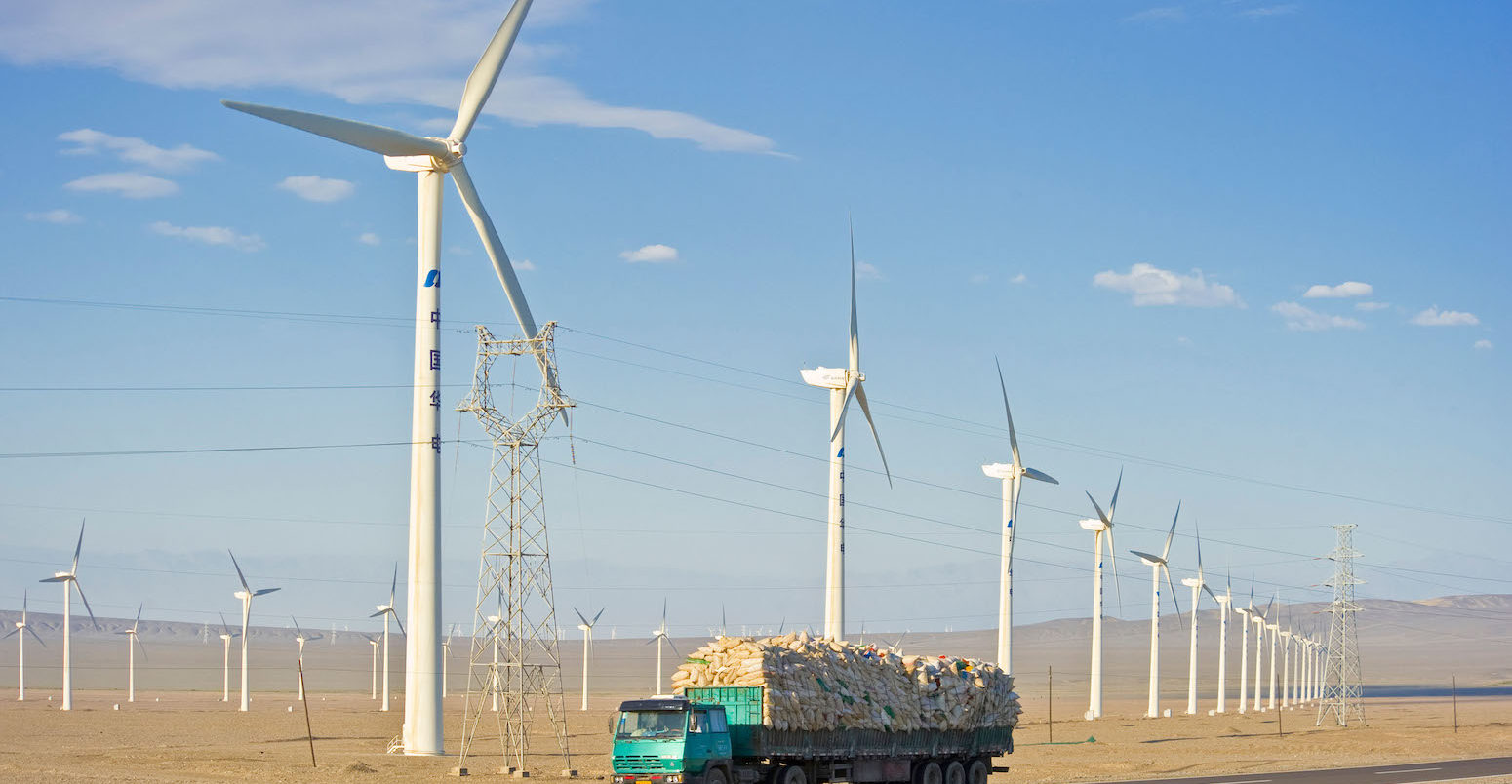 A truck travelling along the G30 Lianhuo expressway with part of the Daheyan wind farm in the background in Xinjiang, China. Credit: Paul Springett D / Alamy Stock Photo