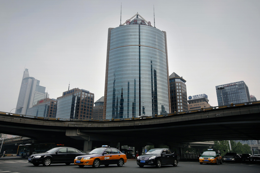 Cars beneath an underpass surrounded by high rise buildings in haze in the business district of Beijing, China