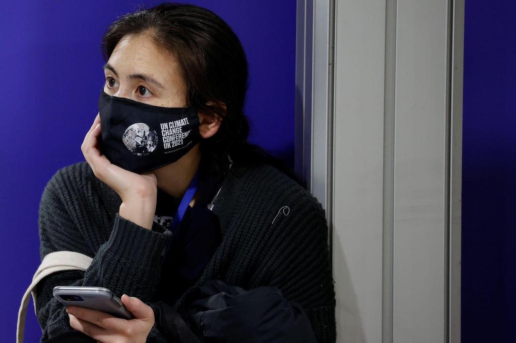 A delegate wears a protective face mask as she checks her phone during the UN Climate Change Conference (COP26) in Glasgow, Scotland, October 31 2021. Credit: REUTERS / Alamy Stock Photo.