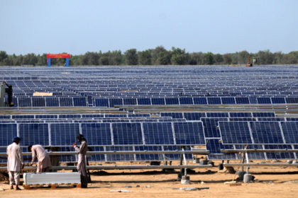 Workers install solar photovoltaic panels in Pakistan.
