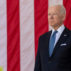 US President Joe Biden stands in front of the United States national flag