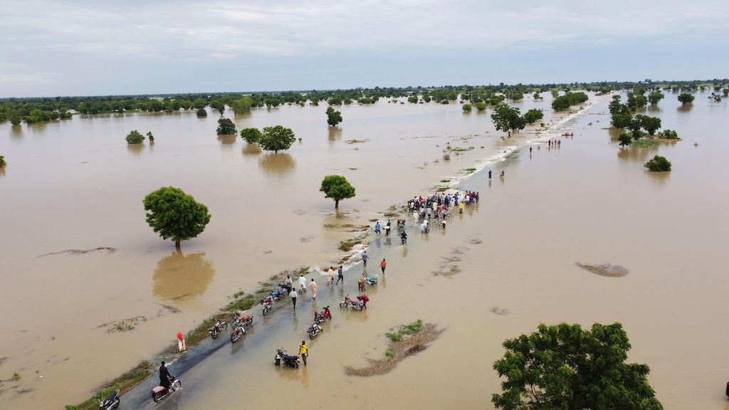 People walk through floodwaters after heavy rainfall in Hadeja, Nigeria, 19 September 2022.