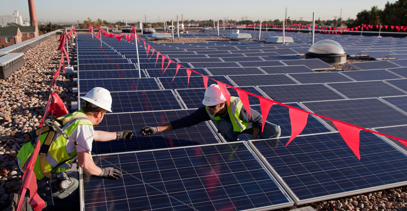 Workers install solar panels on the roof of an elementary school in Colorado.