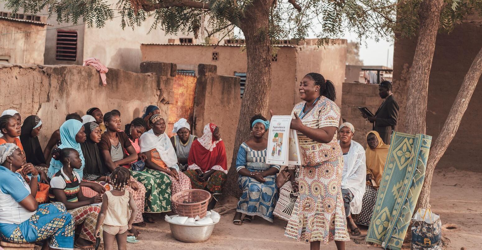 A woman from the health service shows villagers how to prevent malaria in Ouagadougou, Burkina Faso.