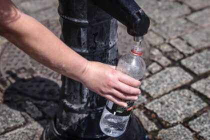 A person pours tap water into a plastic bottle at the Main Square in Krakow, Poland, on 19 June 2022.