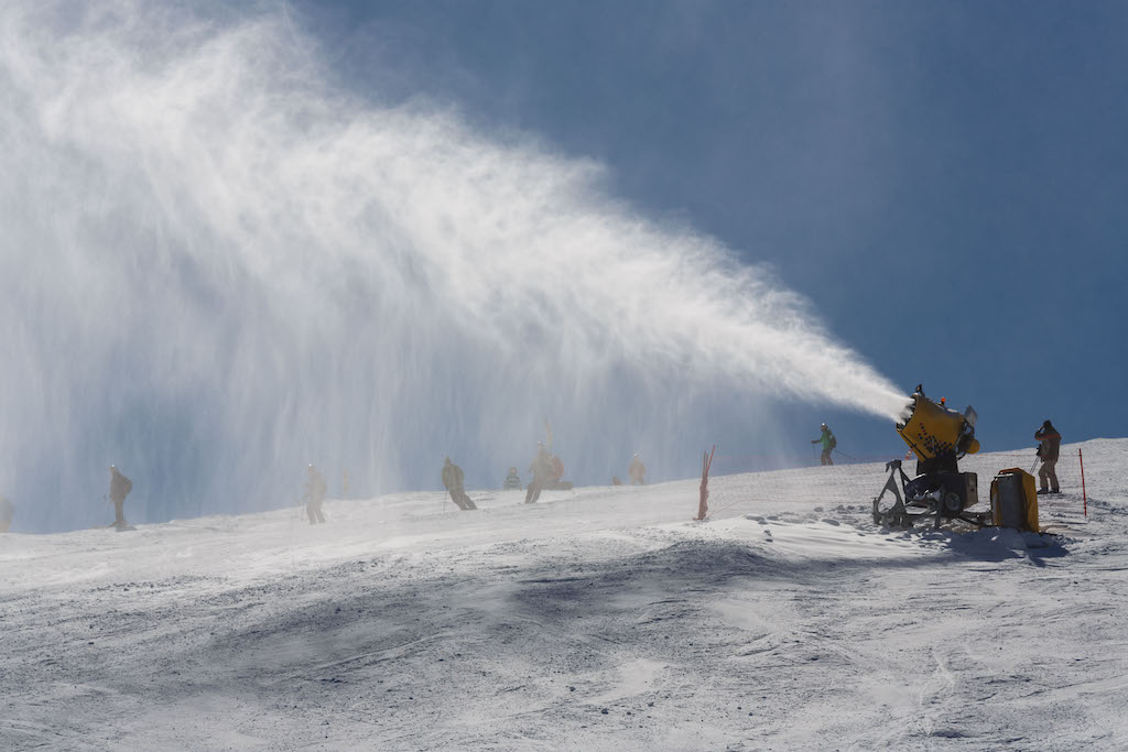 Snowmaker sprays snow on the piste for mountain skiers.